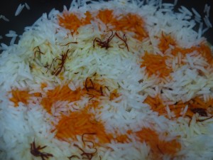 Once you par cook the rice, drain it and add half of it back to the pot, pour the safron water and food color.